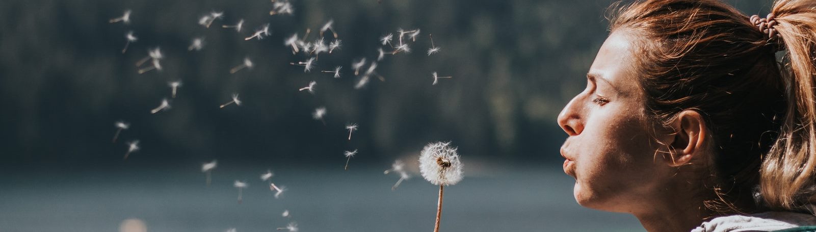 Woman blowing dandelions into the air