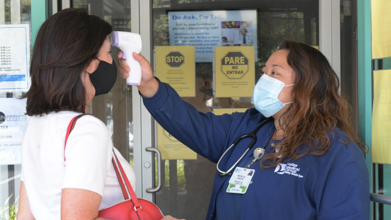 Valley Medical Group nurse taking a patient's temperature before entering the building