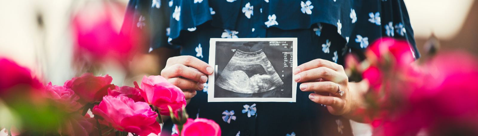 pregnant woman holding ultrasound image of baby