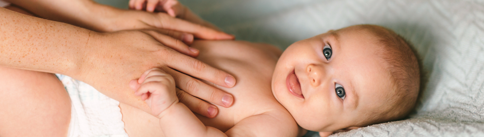 Baby wearing a diaper, smiling at the camera