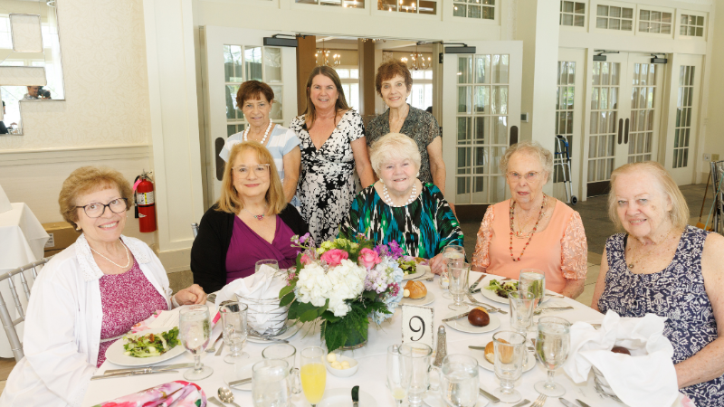 group of women around table posing for a photo