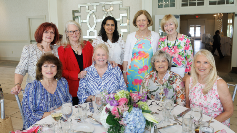 group of women around table posing for a photo