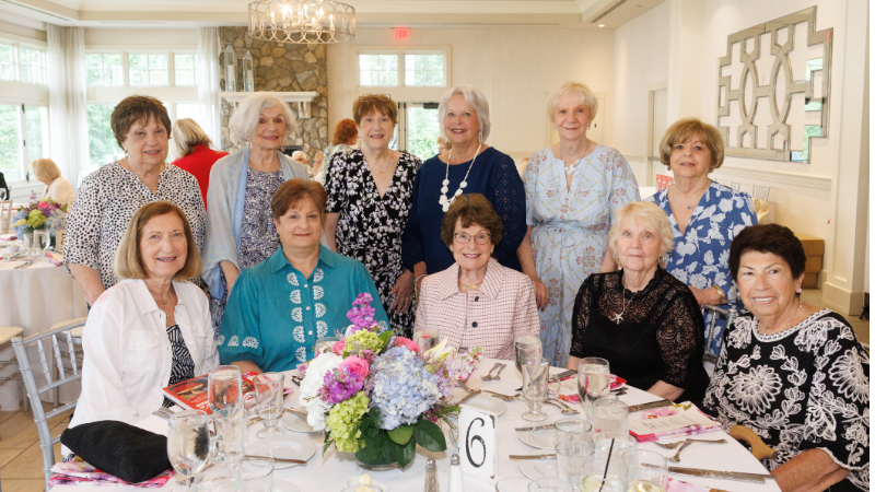 group of women around table posing for a photo