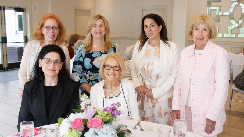 group of women around table posing for a photo
