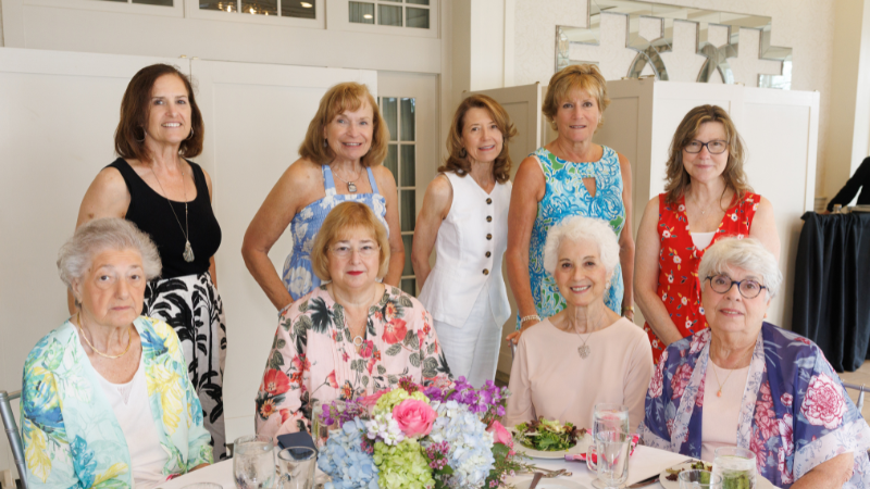 group of women around table posing for a photo