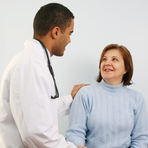 Male doctor smiling and speaking with a smiling female patient.