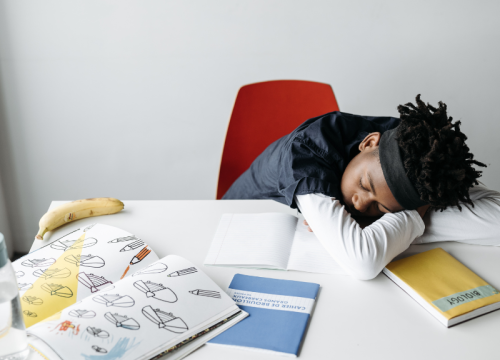 child sleeping with a pile of books on the desk