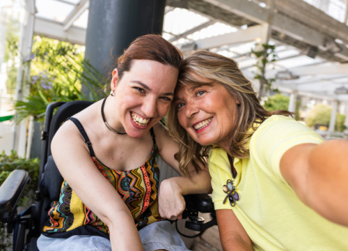 woman in a wheelchair smiling with another woman
