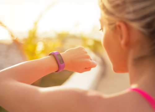 woman looking at the wearable fitness tracker on her wrist
