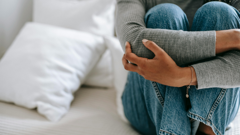 girl with anxiety holding herself on couch