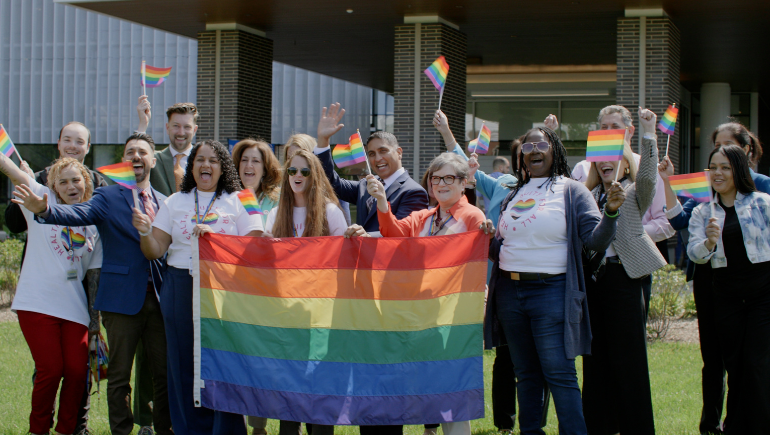 group of employees holding pride flag