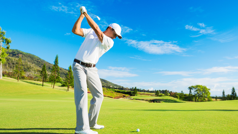 man swinging golf club outside