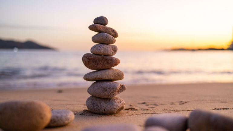 tranquil and peaceful stones stacked on a beach at sunset
