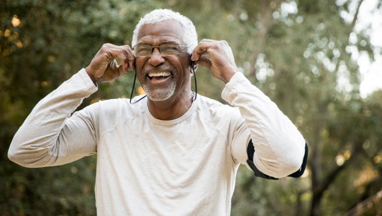 older man smiling while putting in headphones