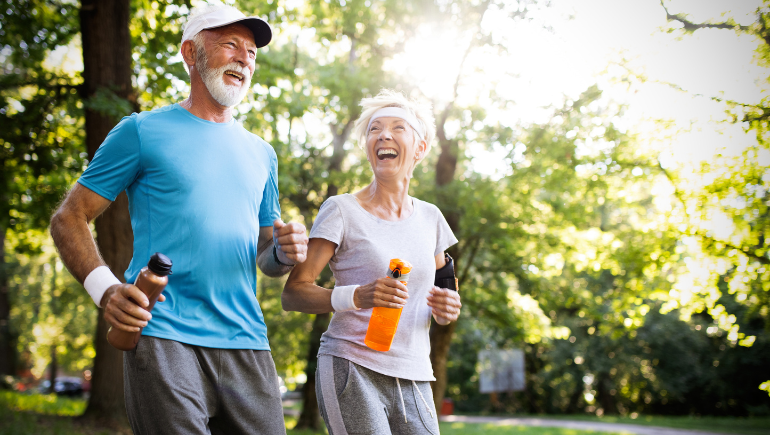 two senior citizens smiling holding water bottles while working out in the park