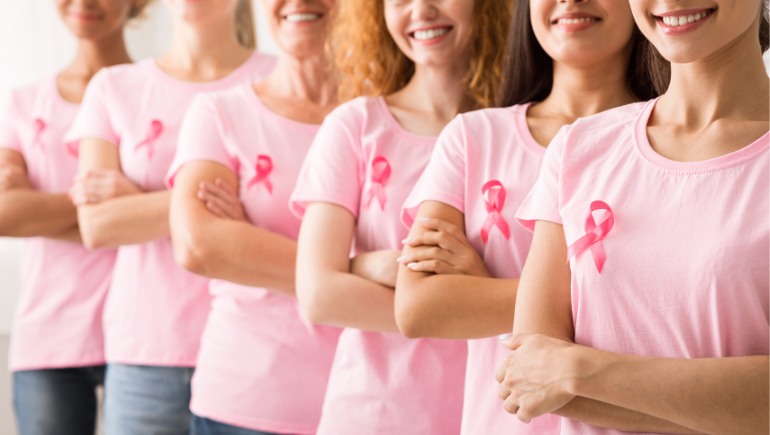 women smiling wearing pink breast cancer awareness ribbons