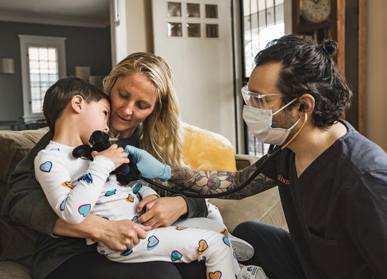 DispatchHealth provider checking a pediatric patient with stethoscope