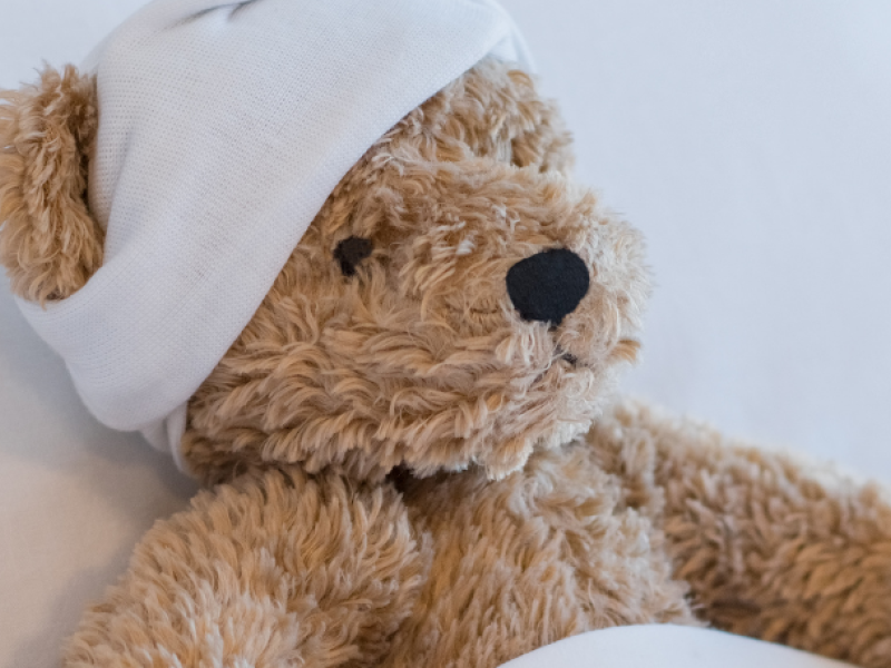 teddy bear in bed with bandage on his head