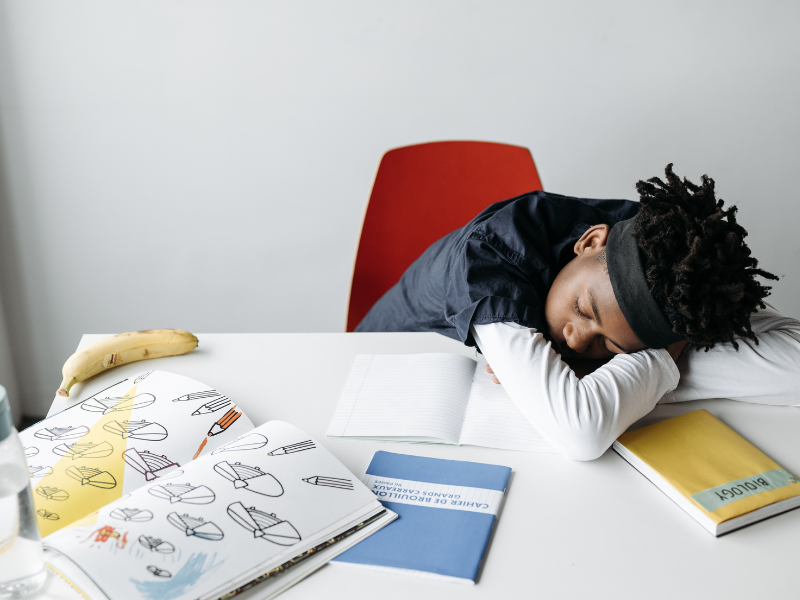 child sleeping with a pile of books on the desk