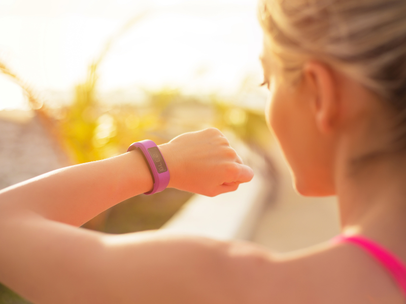 woman looking at the wearable fitness tracker on her wrist